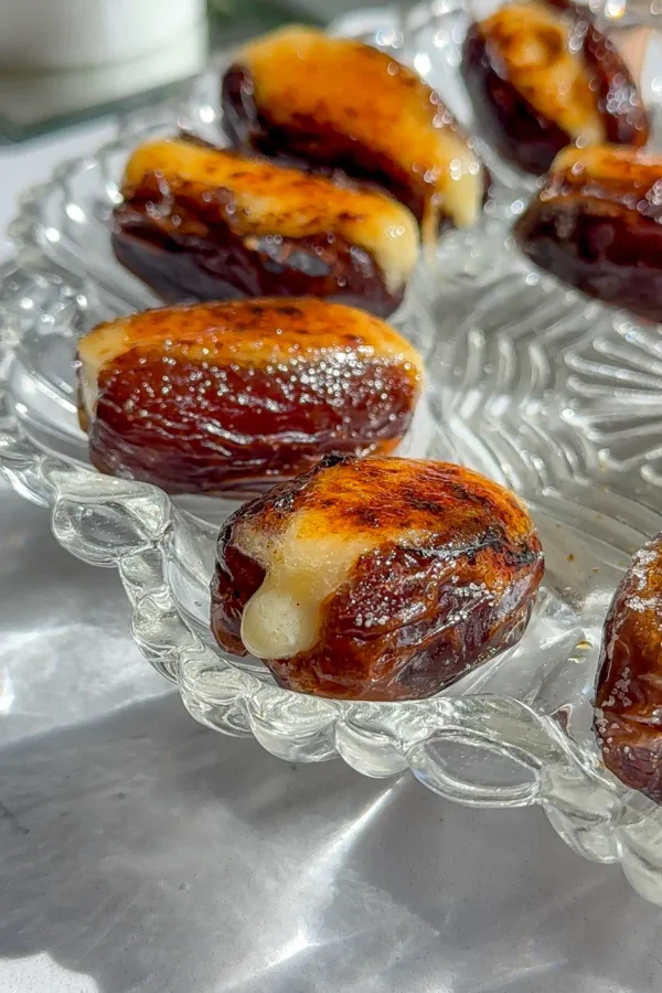 Close up of Medjool dates stuffed with whipped brie and topped with a shattered caramelized sugar crust.