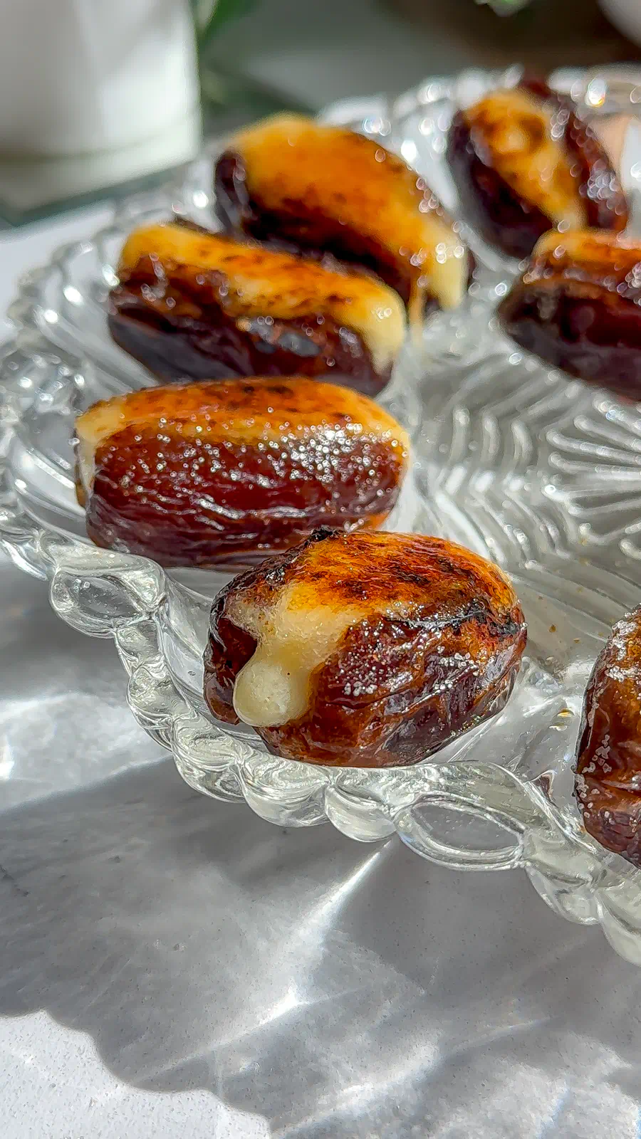 Close up of Medjool dates stuffed with whipped brie and topped with a shattered caramelized sugar crust.