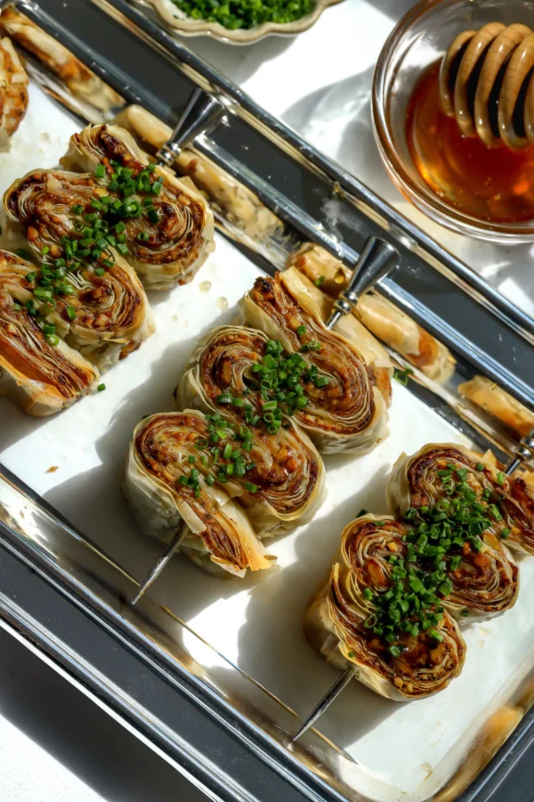 Overhead view of crispy phyllo with whipped feta and honey appetizers arranged on a silver tray.