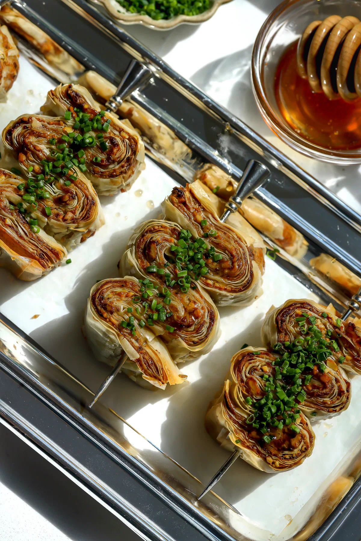 Overhead view of crispy phyllo with whipped feta and honey appetizers arranged on a silver tray.