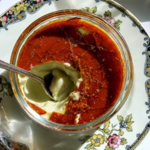 A spoon breaking through the hard caramel shell of a creamy pistachio creme brulee made without a kitchen torch.