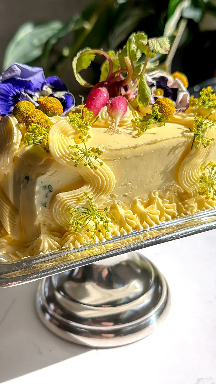 A close-up of a butter cake showing the intricate star and ruffle piping details on the sides.