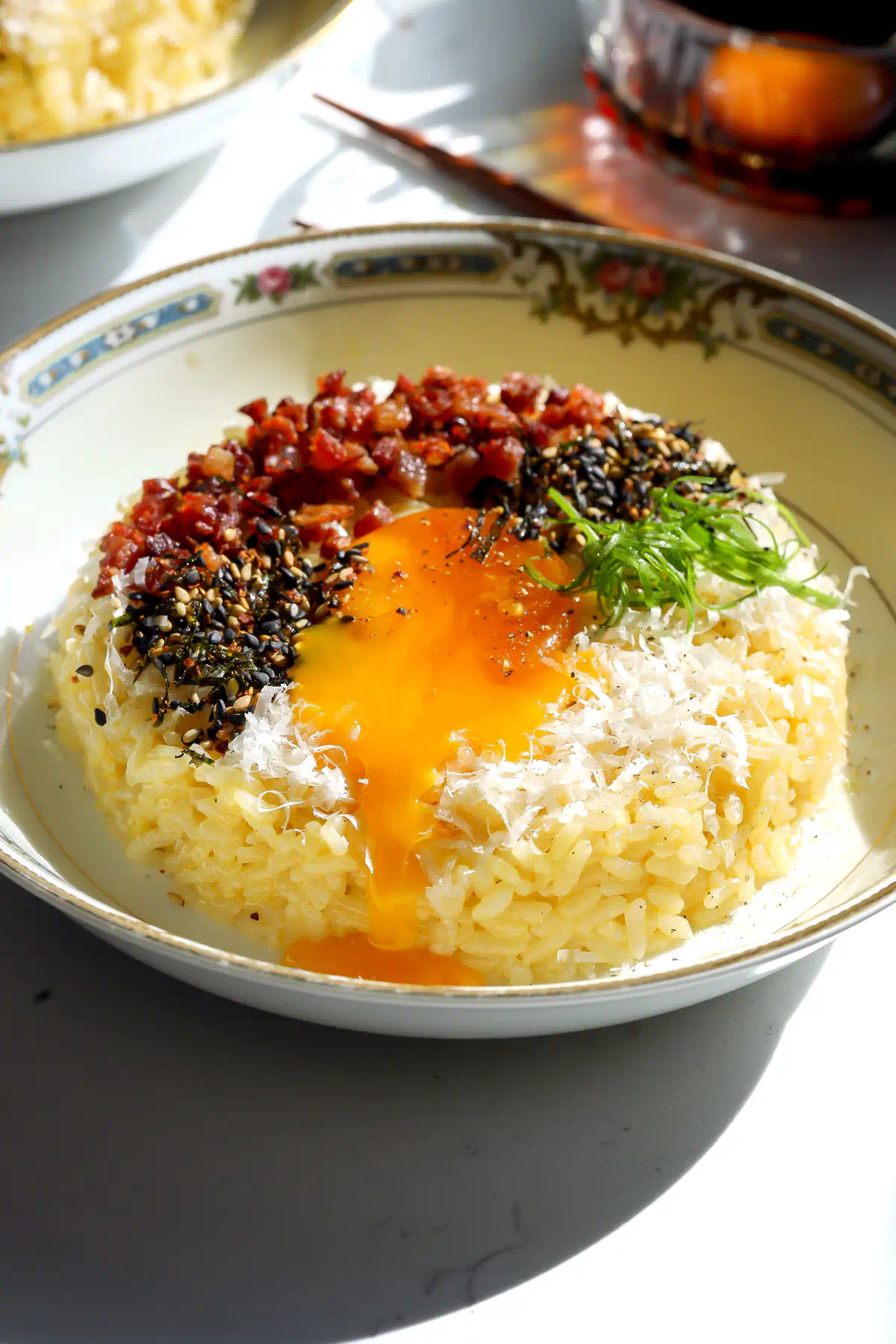 A close-up action shot capturing the golden, liquid center of a cured egg yolk breaking over a creamy, umami-rich Wafu-style Carbonara TKG rice bowl.