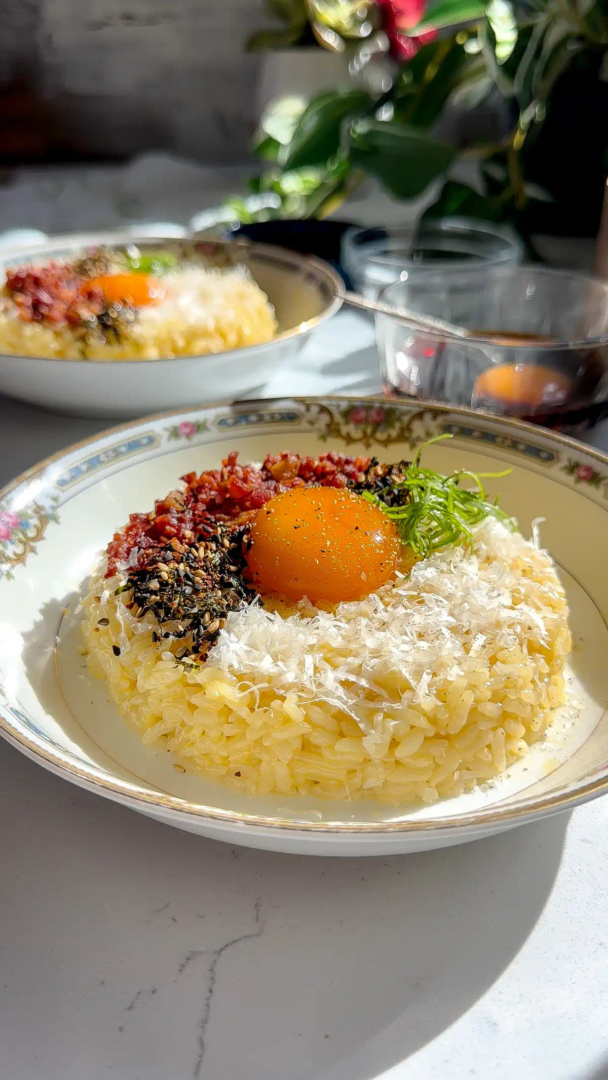 A sun-drenched lifestyle shot of two bowls of Wafu Carbonara Tamago Kake Gohan served in an aesthetic, high-contrast brunch setting with natural window light.