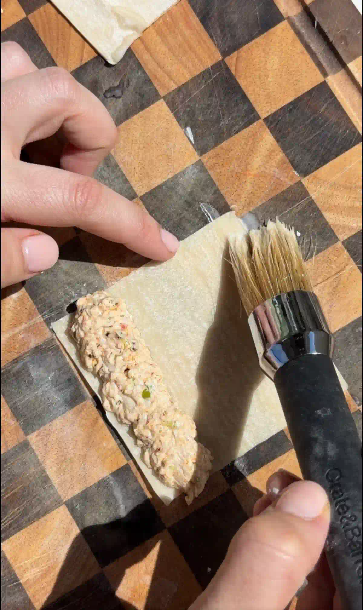 Brushing the wonton wrapper with water and cornstarch with the crab mixture inside.