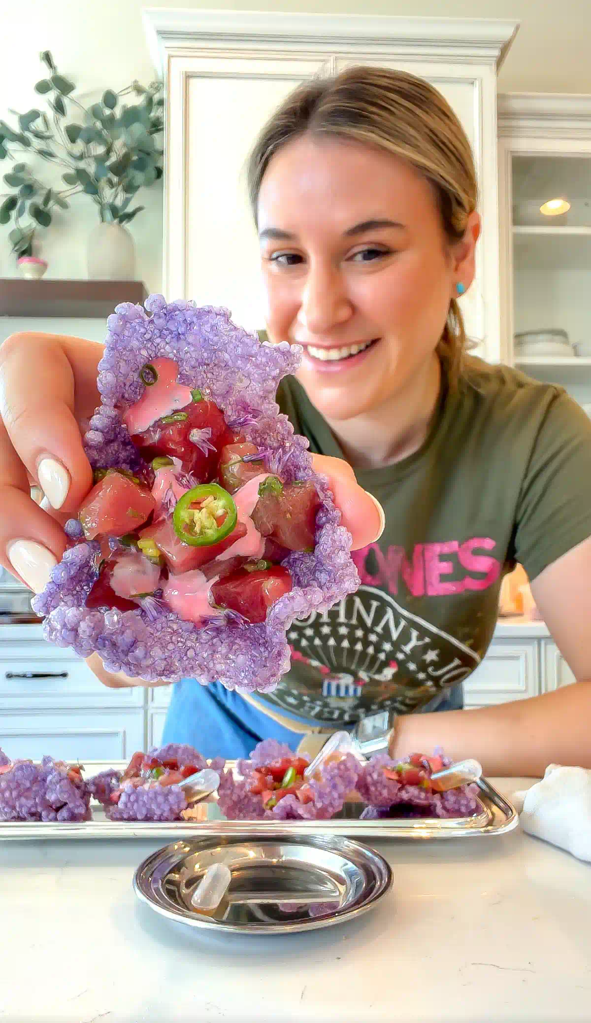Nadia holding a bright purple tapioca crisp topped with cured bluefin tuna, pink beet-ginger mayo, and a serrano slice.