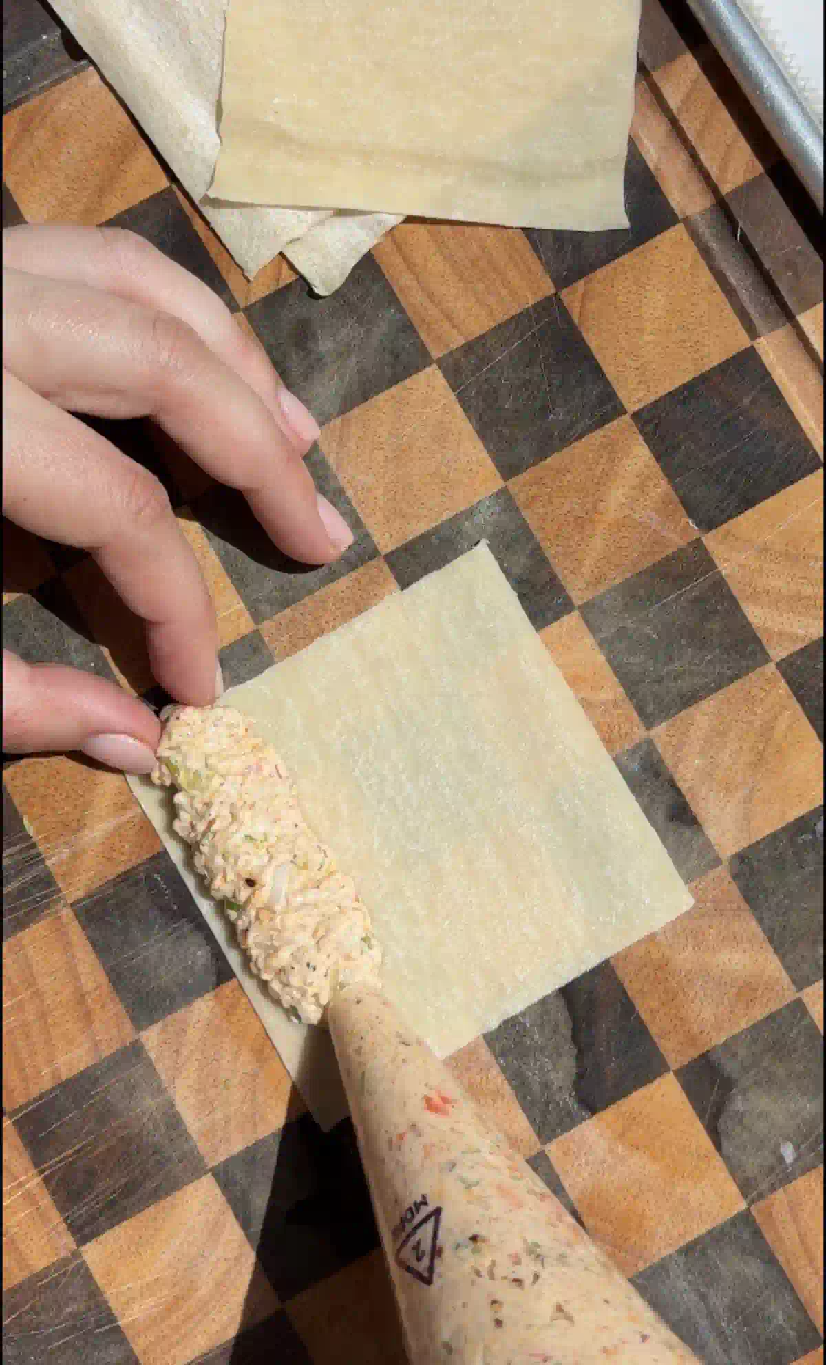 Piping the crab Rangoon mixture in a line on the wonton wrapper.
