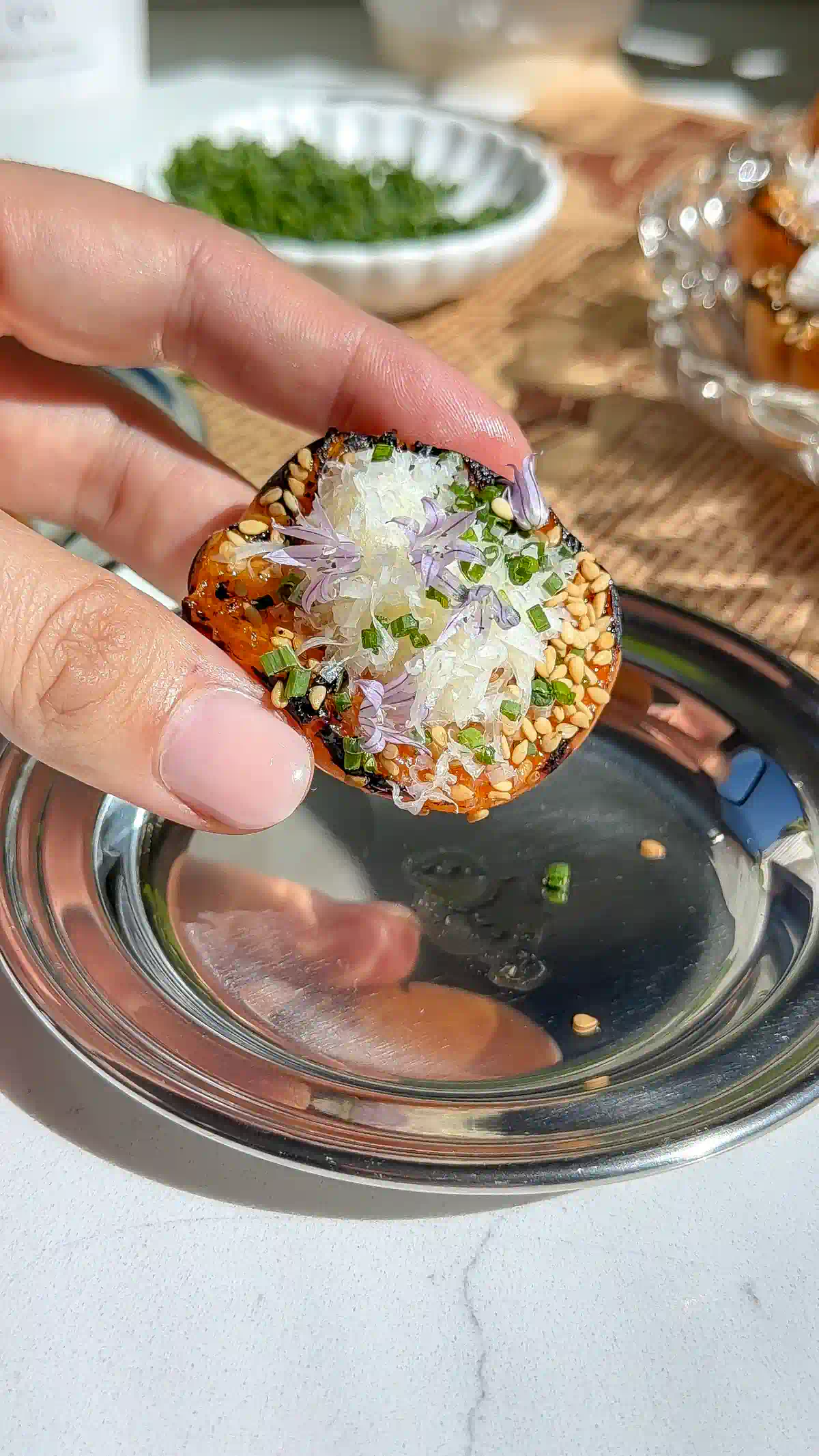 Charred grilled apricot half rimmed with toasted sesame seeds and topped with a white cheese rosette and chive blossoms