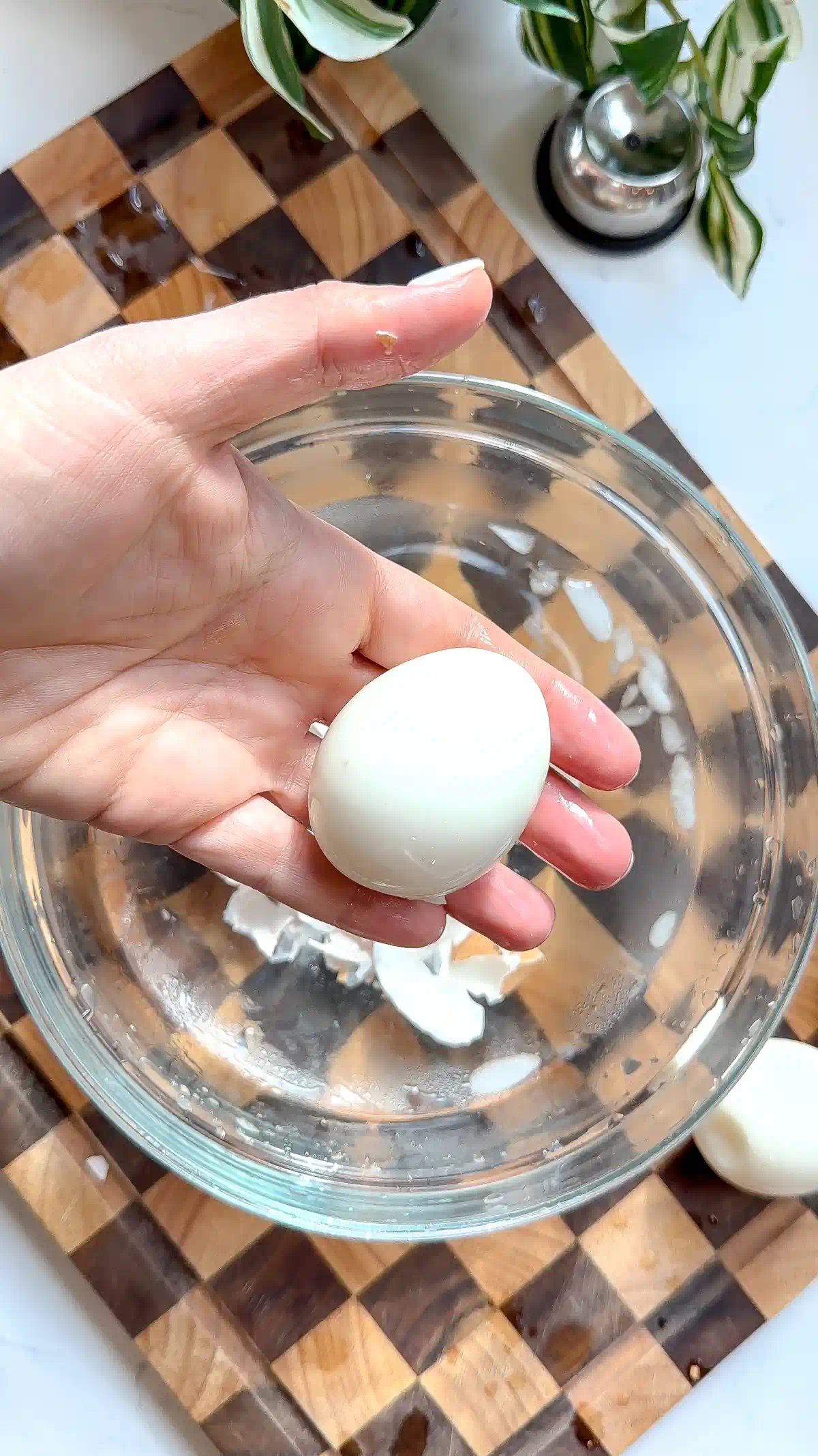 A hand holding a smooth, fully peeled soft boiled egg