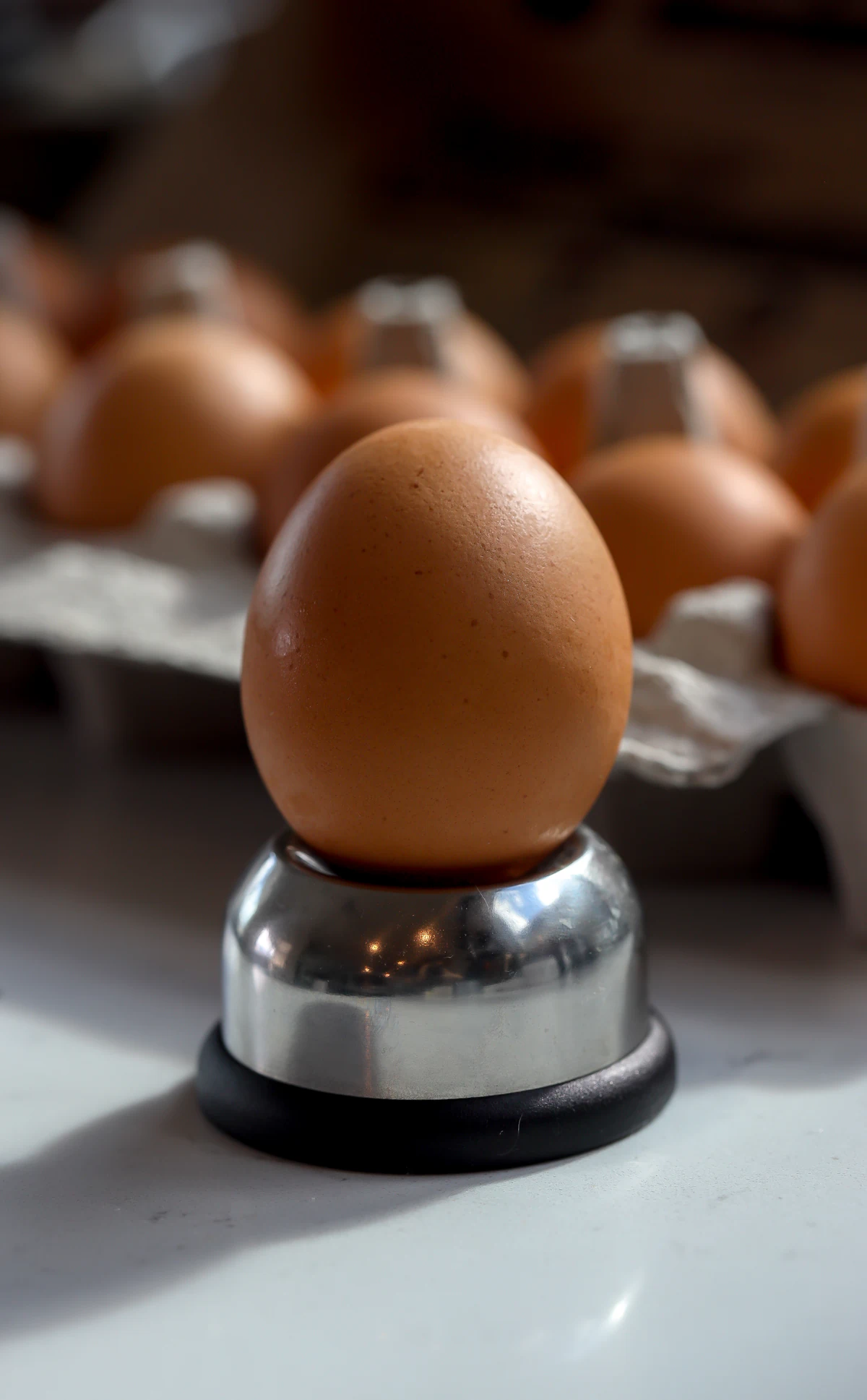 A brown egg balanced fat end down on a metal egg piercer