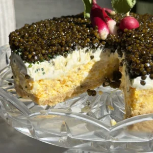 Caviar pie with a slice removed, showing the ritz cracker crust under the egg mousse and crème fraîche.