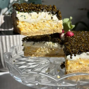A slice of caviar pie lifted from the stand, showing the ritz crust, egg mousse, crème fraîche, and caviar layers.