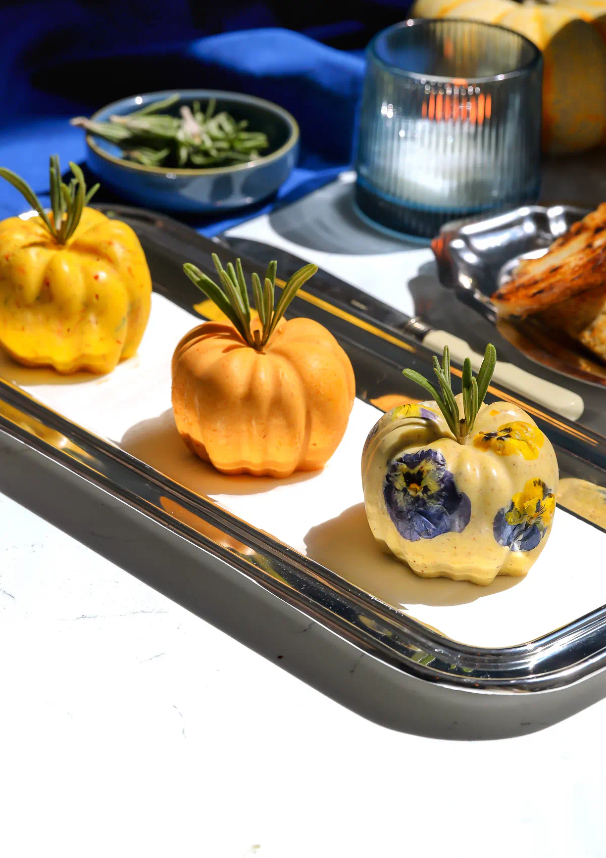 Roasted garlic pumpkin, pumpkin cinnamon roll, and maple pecan brown butter pumpkins lined up on a silver serving tray.